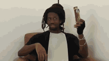 a man with dreadlocks is sitting in a chair holding something