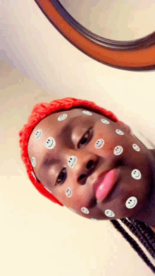a person with smiley faces on their face wearing a red hat