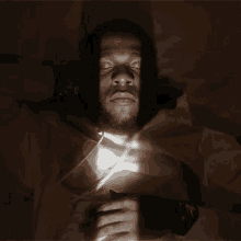 a man laying down with his eyes closed and a light shining on his chest