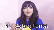 a woman in a blue shirt is holding a bag of chips with ay pobre tonta written on it .
