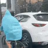 a person wearing a blue raincoat is riding a bike