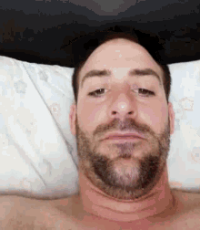 a shirtless man with a beard is laying on a bed