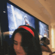 a woman wearing a red headband is standing in front of a screen