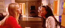 two women are sitting at a table and kissing each other