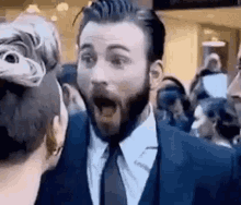 a man in a suit and tie is making a surprised face while standing next to a woman .