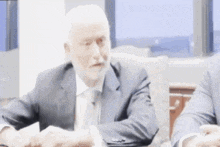 a man in a suit and tie is sitting at a table shaking hands .