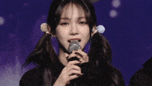 a girl with pigtails is singing into a microphone while another girl watches .