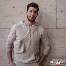 a man with a beard is wearing a white hoodie with a small pocket on the side .