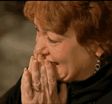 a woman with a ring on her finger covering her mouth with her hands