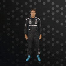 a man in a petronas suit stands in front of a black background