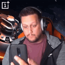 a man wearing headphones looks at a cell phone with a oneplus logo in the corner