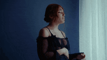 a woman in a black dress is looking out of a window