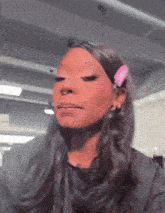 a woman with long black hair and a pink clip in her hair is making a face .