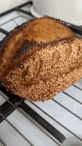 a loaf of bread with sesame seeds is sitting on a cooling rack