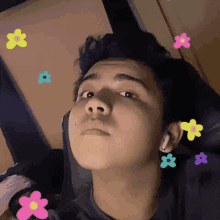 a young man is sitting in a chair with flowers coming out of his ears .