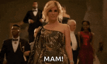 a woman in a sequined dress is standing in front of a group of people and says mam
