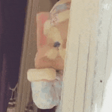 a stuffed animal is peeking out from behind a wooden door .