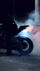 a person is riding a motorcycle at night with smoke coming out of the tire