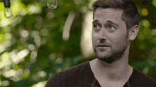 a man with a beard is standing in front of a green background