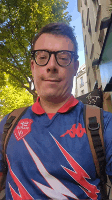 a man wearing glasses and a blue shirt with the number 92 on the front