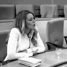 a woman in a white jacket sits at a table