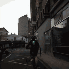 a person riding a bike down a street in front of a sign that says " malaise "