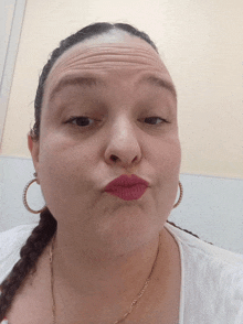 a woman wearing hoop earrings and red lipstick makes a face