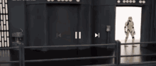 a storm trooper is standing in front of a door in a room with a fence .