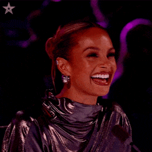 a woman is smiling in front of a microphone with a star in the upper right corner