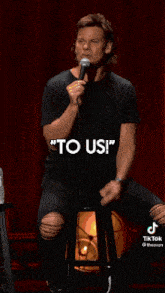 a man is holding a microphone in front of a red curtain and talking into it .
