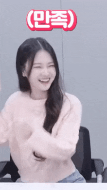 a woman in a pink sweater is sitting in a chair laughing .