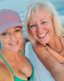 two women are posing for a picture and one is wearing a pink hat that says fishing paradise