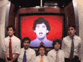a group of men standing in front of a red screen