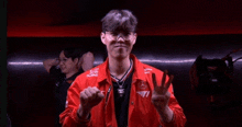 a man in a red jacket is making a peace sign with his hands .