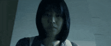 a close up of a woman 's face in a dark room with a blurred background .