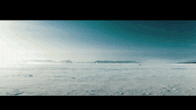 a large snowy field with mountains in the background