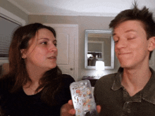 a man and a woman are looking at each other while holding a phone