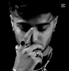 a close up of a man wearing earrings and a necklace making a funny face .
