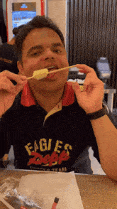 a man wearing an eagles shirt is eating a piece of food