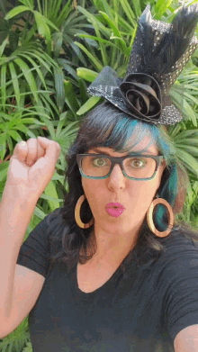 a woman with blue hair and glasses holds her fist up in the air