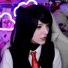 a girl with black hair and a red tie is sitting in front of a purple light .