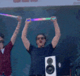 a man wearing sunglasses is holding up a rainbow light stick