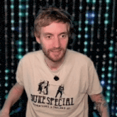 a man wearing a duke special shirt is standing in front of a curtain of lights