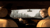 a man and a woman are sitting in a car looking out the window
