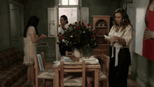 a woman standing in a room with a vase of flowers