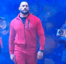 a man in a red jacket and pants is walking down a stage .