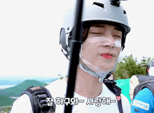 a man wearing a helmet with a clear mask on his face says " i love you " in korean