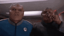 two aliens are standing next to each other smoking cigarettes