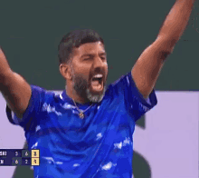 a man in a blue shirt is screaming while playing tennis
