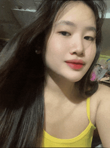 a woman with long hair is wearing a yellow tank top and red lipstick
